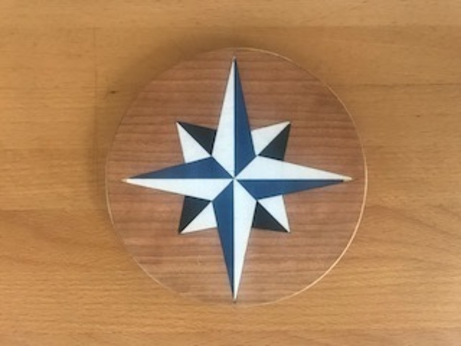 A blue and white natuical star inlay on a round wooden plate.